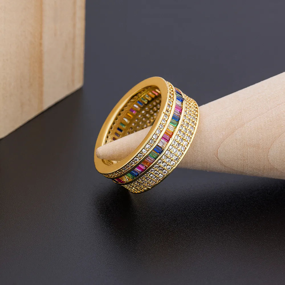 Anel dourado feminino com zircônias coloridas e detalhes cravejados, design delicado e elegante.