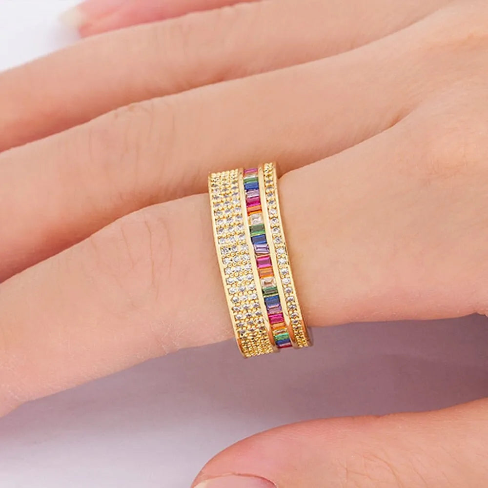 Anel dourado feminino com zircônias coloridas e detalhes cravejados, design delicado e elegante.