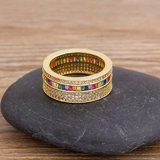 Anel dourado feminino com zircônias coloridas e detalhes cravejados, design delicado e elegante.