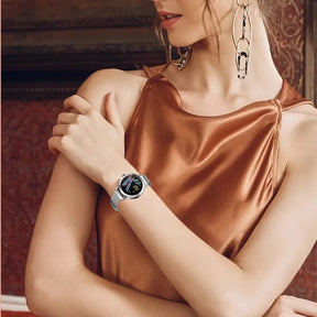 Smartwatch feminino prata com tela AMOLED, pulseira em aço fino e monitoramento de saúde completo.