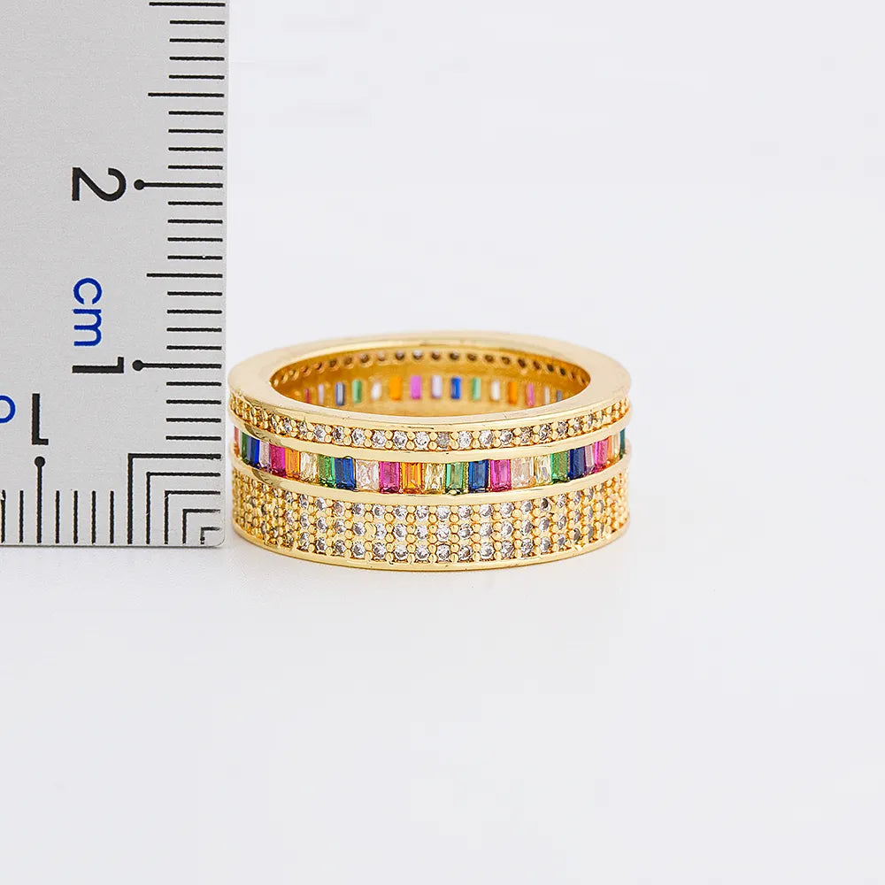 Anel dourado feminino com zircônias coloridas e detalhes cravejados, design delicado e elegante.