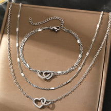 Conjunto com colar e pulseira em aço inox dourado ou prata com pingente de corações entrelaçados