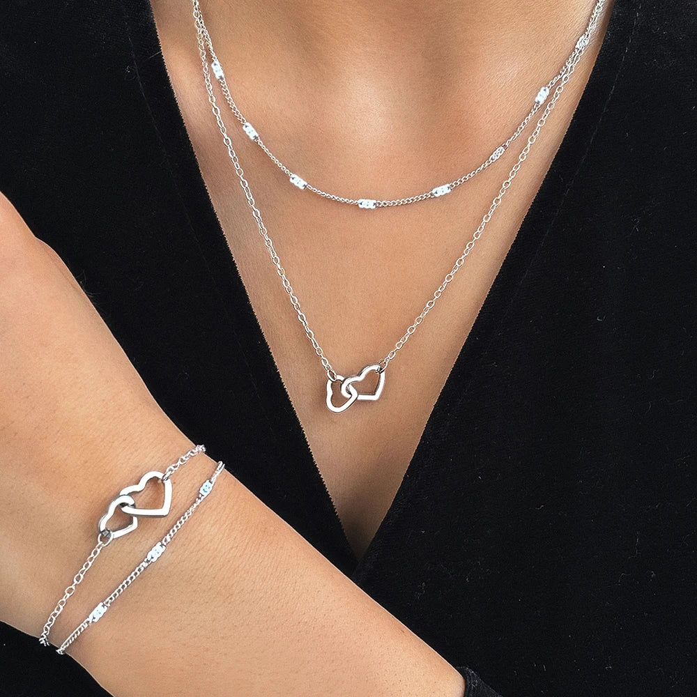 Conjunto com colar e pulseira em aço inox dourado ou prata com pingente de corações entrelaçados