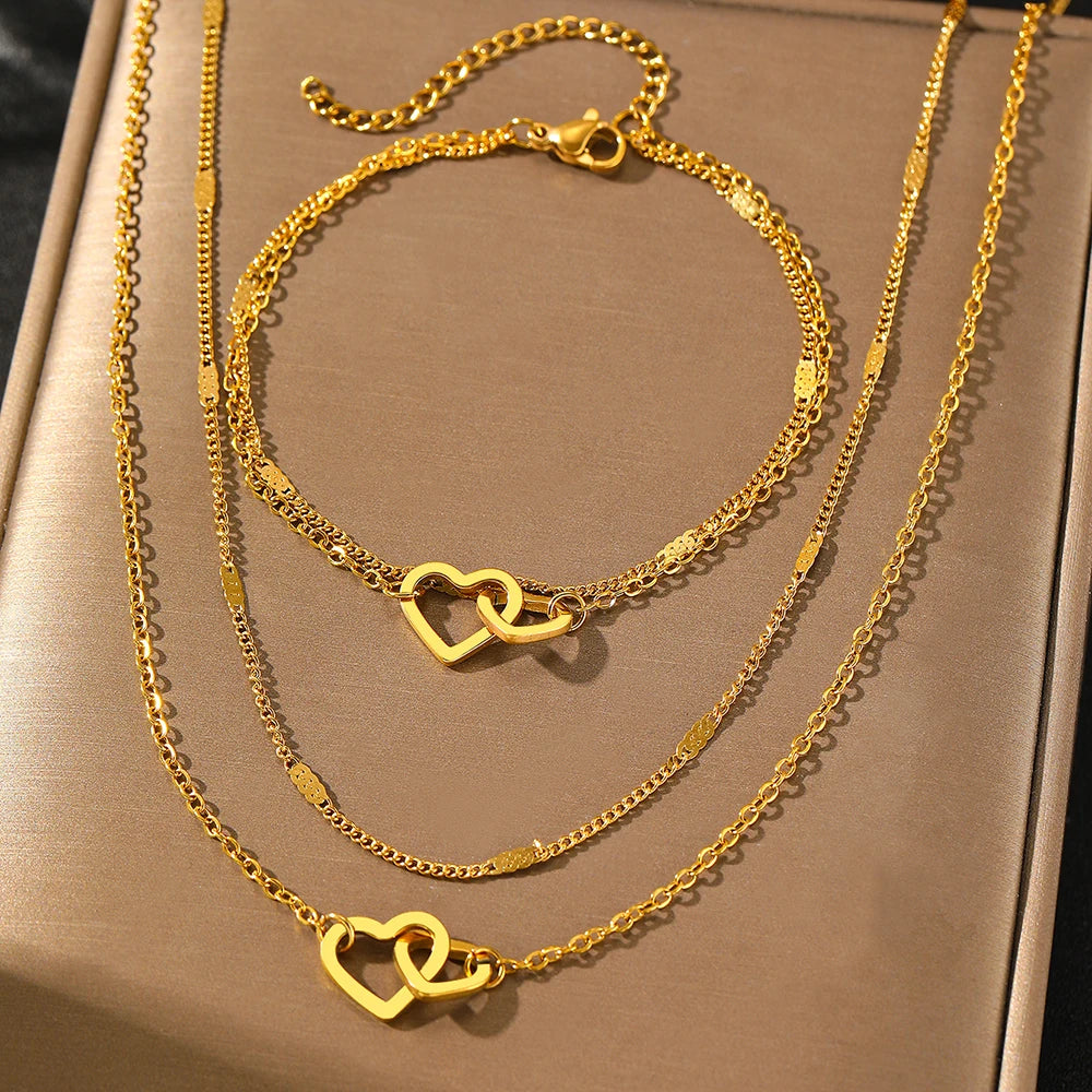 Conjunto com colar e pulseira em aço inox dourado ou prata com pingente de corações entrelaçados