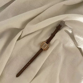 Relógio feminino Elegante com pulseira marrom de couro e mostrador quadrado dourado.