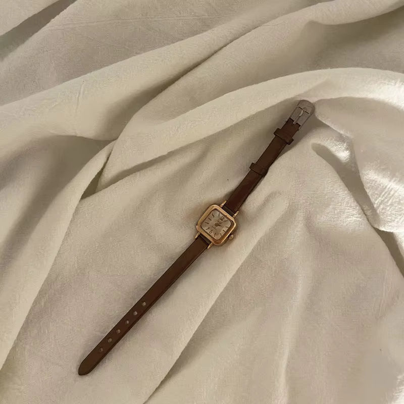 Relógio feminino Elegante com pulseira marrom de couro e mostrador quadrado dourado.