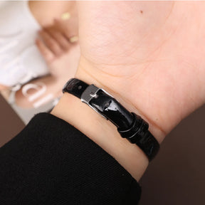 Relógio feminino com pulseira preta de couro e mostrador quadrado dourado.